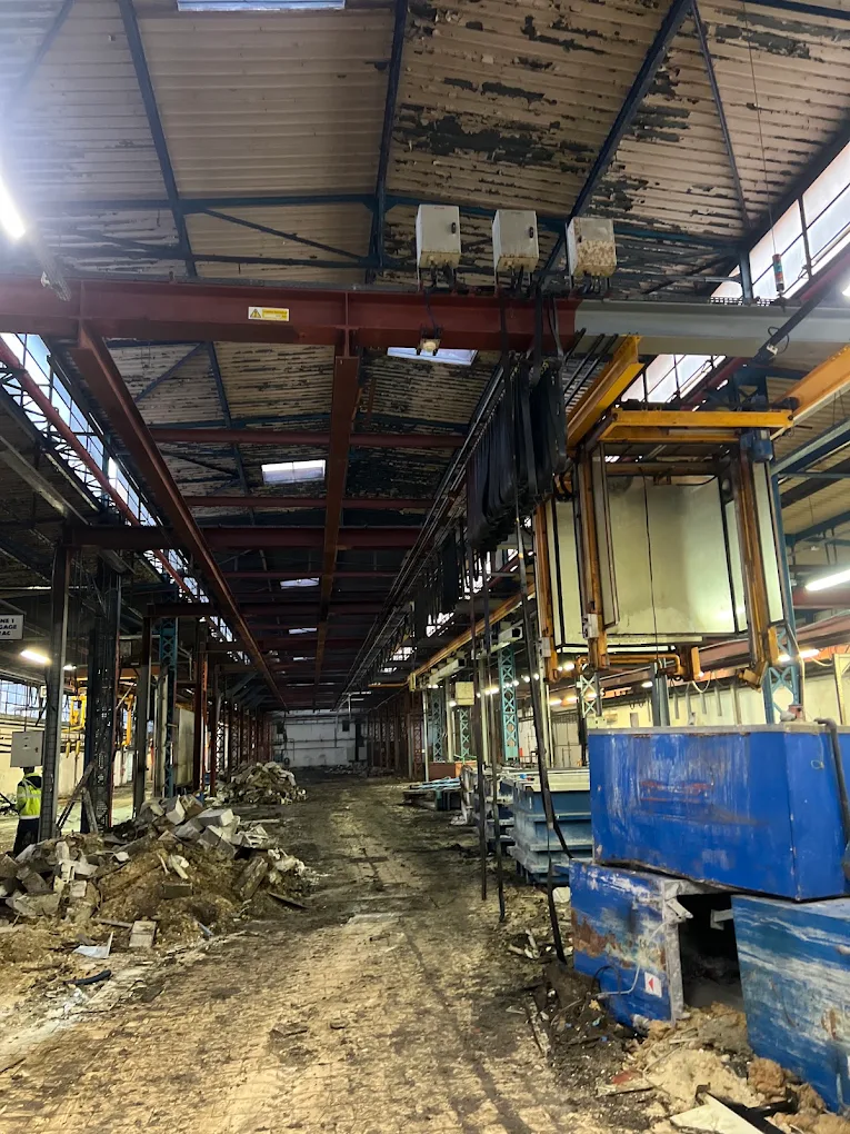 Hall d’usine avec cuves bleues et chaîne de traitement à démanteler